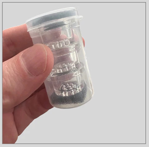 Close-up of Weedgets MAZE-X Pipe Borosilicate Glass Bowl 3-Pack in clear container held by fingers