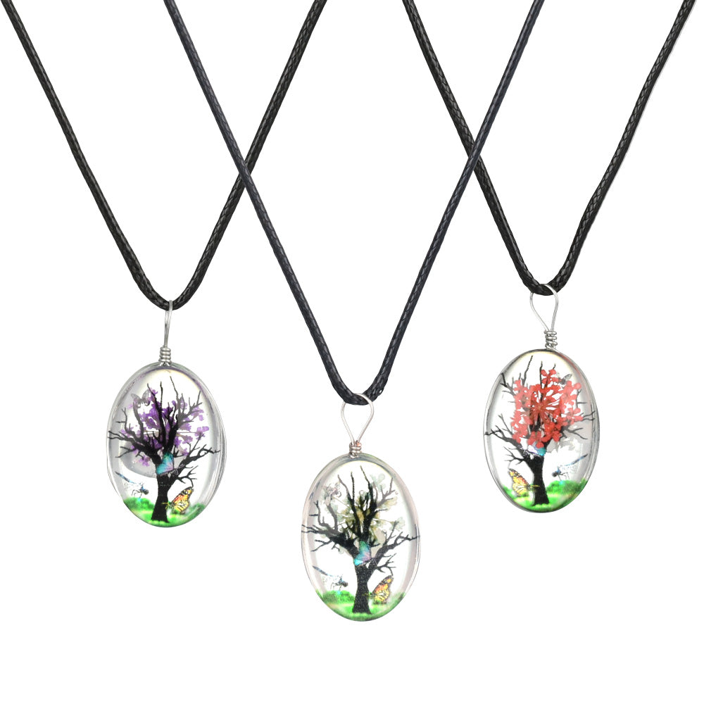 Assorted oval glass pendants with blooming tree designs on black necklaces, front view