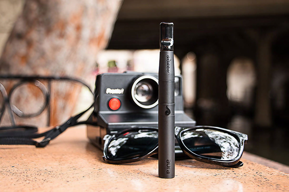 Dr Dabber Aurora Vaporizer LIMITED Aaron Kai Edition on table with sunglasses