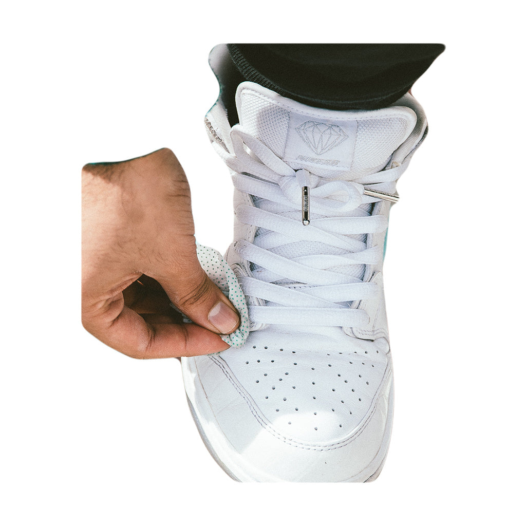 Person using Hemper Tech Alcohol Freshwipes to clean white sneaker, close-up view