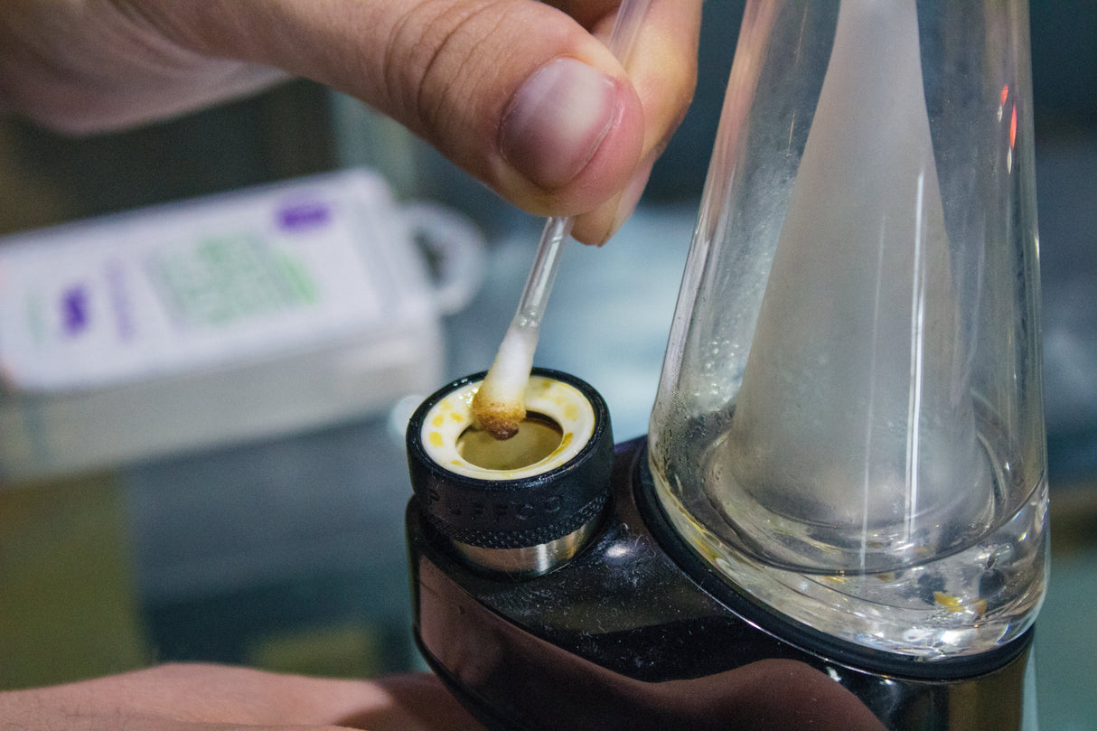 Hemper Tech Snapcap Alcohol Swab in use cleaning a glass bong bowl, close-up view