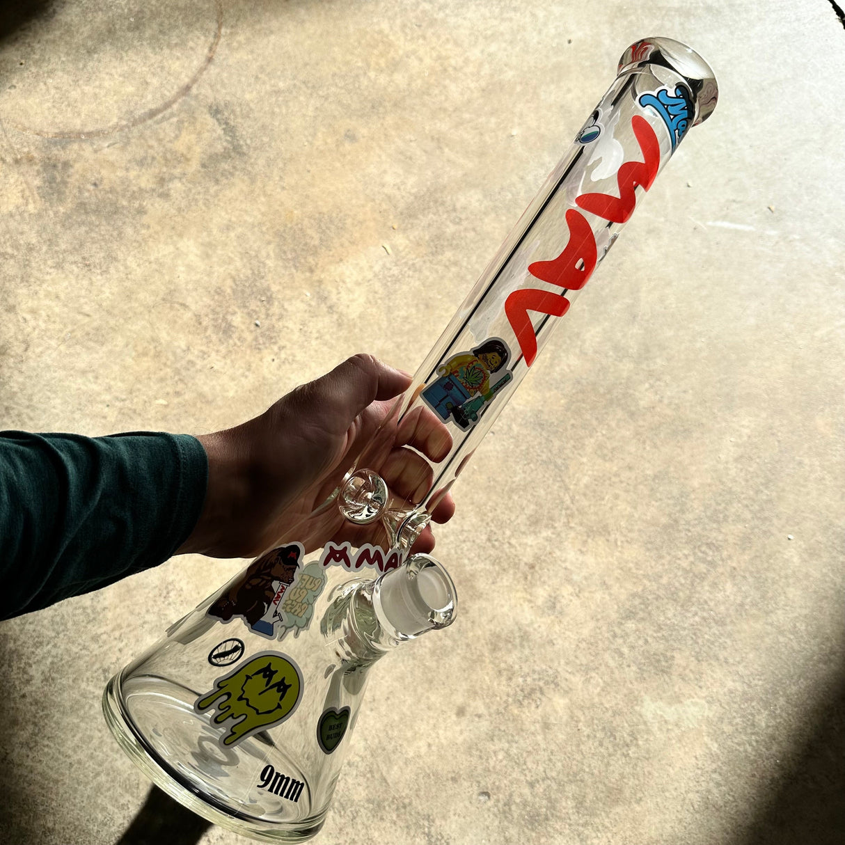 Person holding MAV Beaker Bong decorated with assorted vinyl stickers from MAV Beaker Sticker Pack