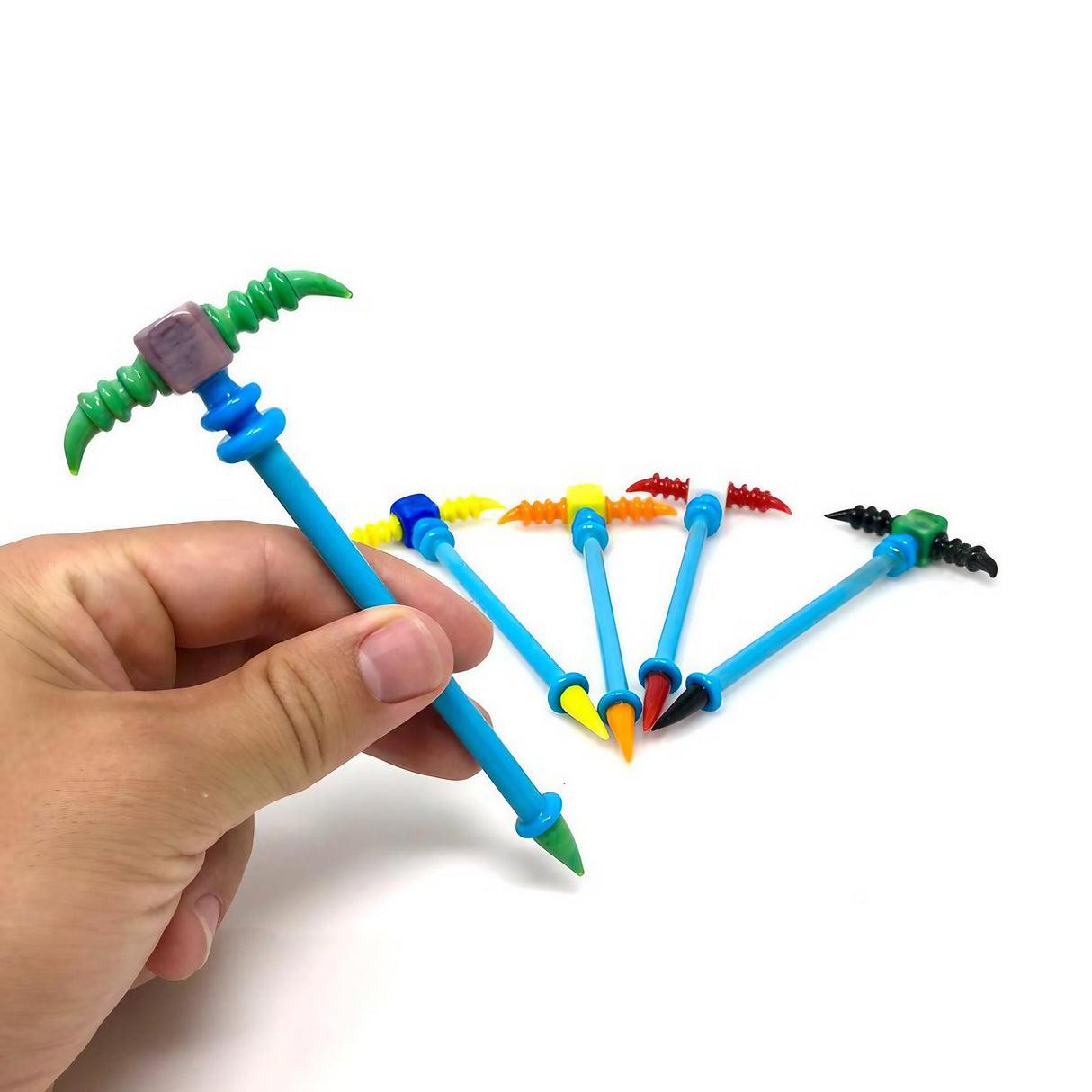 Assorted colors Tri-Point Dabber by DankGeek, held in hand, showing textured grip and pointed end