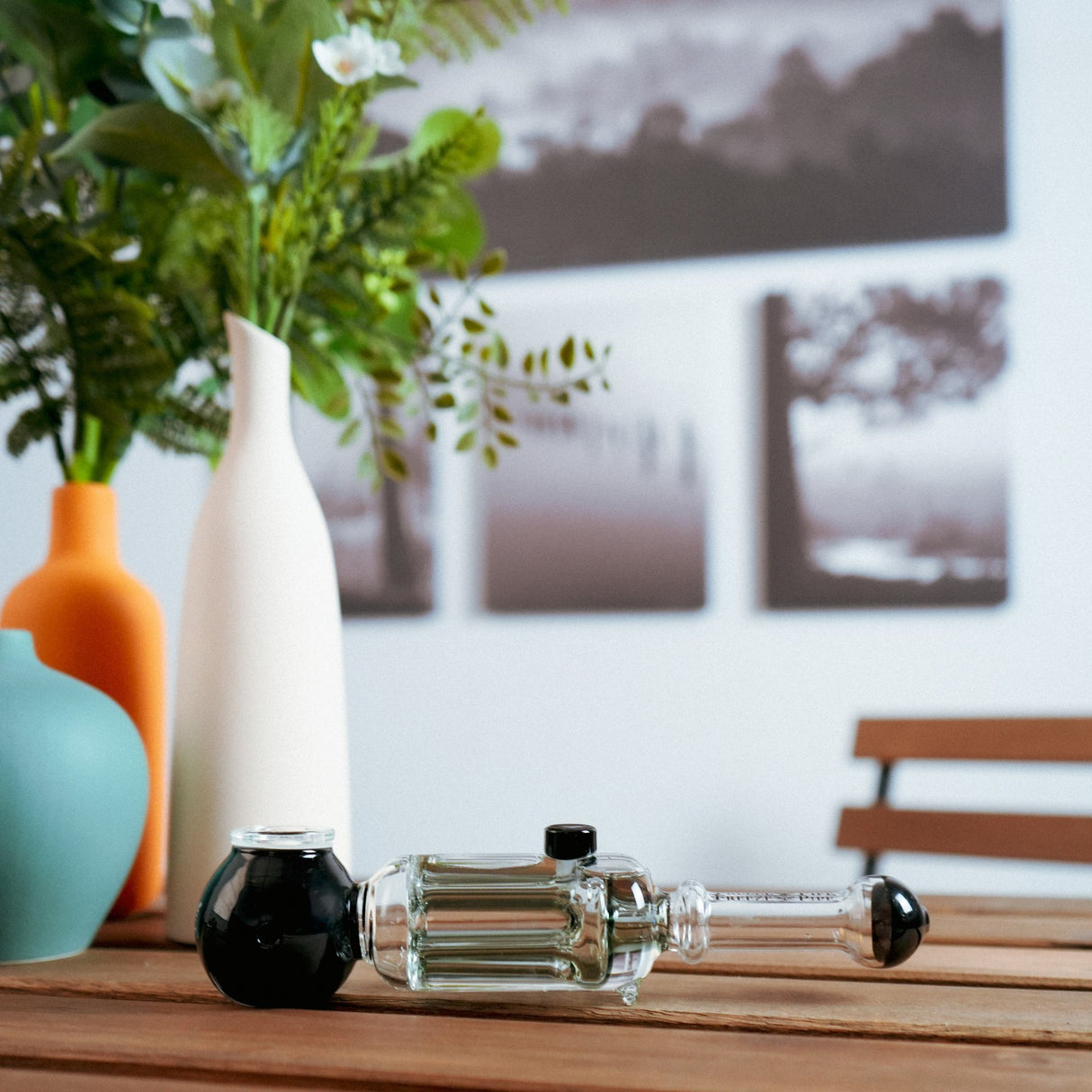 Freeze Pipe Revolver on wooden table with stylish vases, side view showcasing its unique design