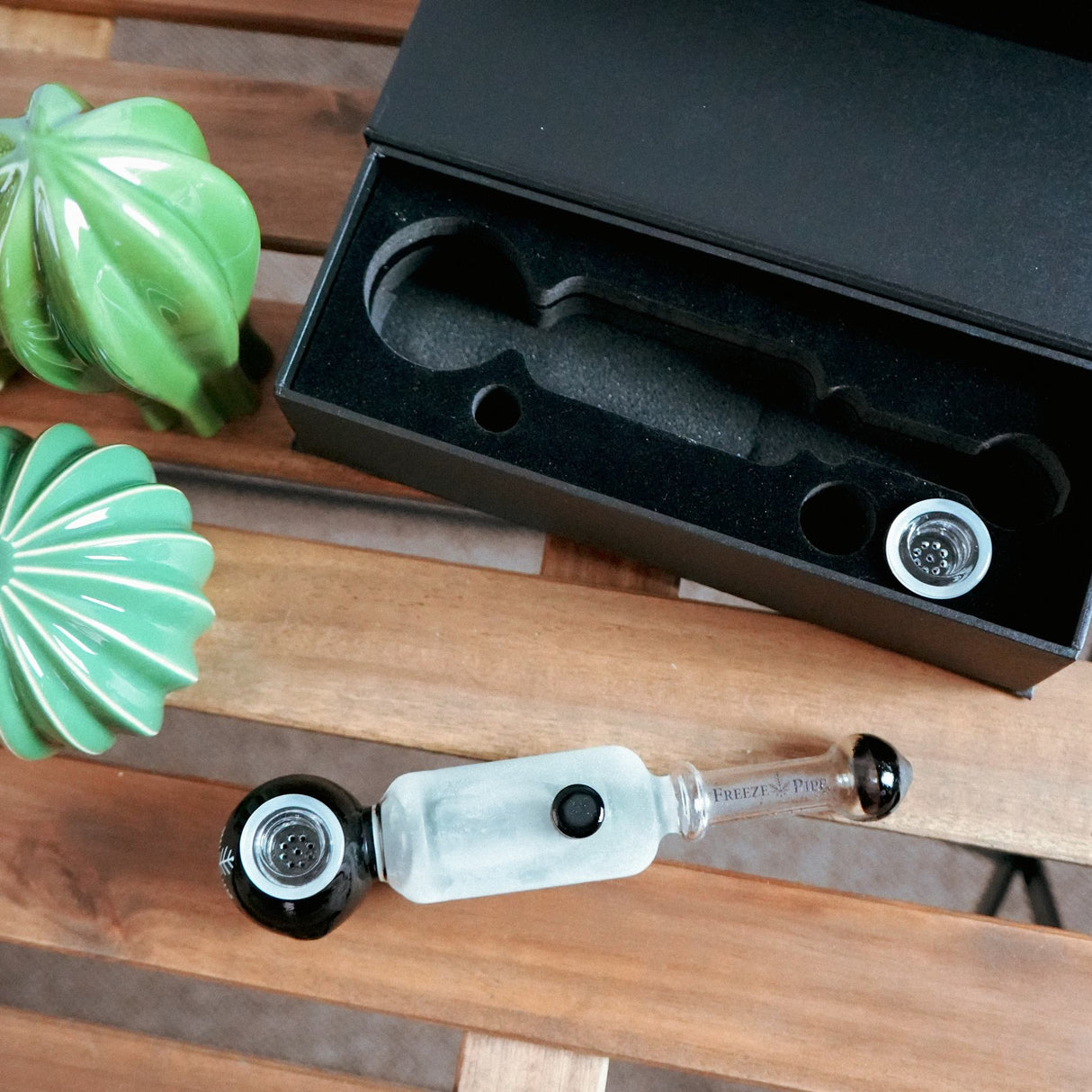 Freeze Pipe Revolver with glass bowl and cooling chamber, displayed beside its box on a wooden surface