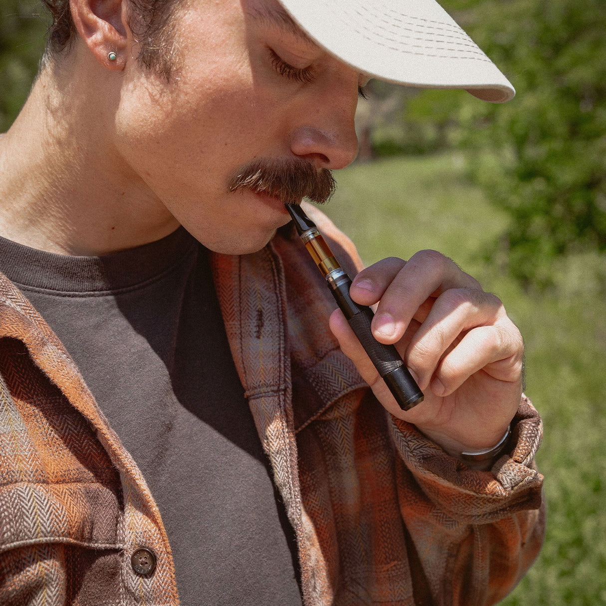 Man using EDC Field Pen Vape Battery outdoors, showcasing its portability and ease of use
