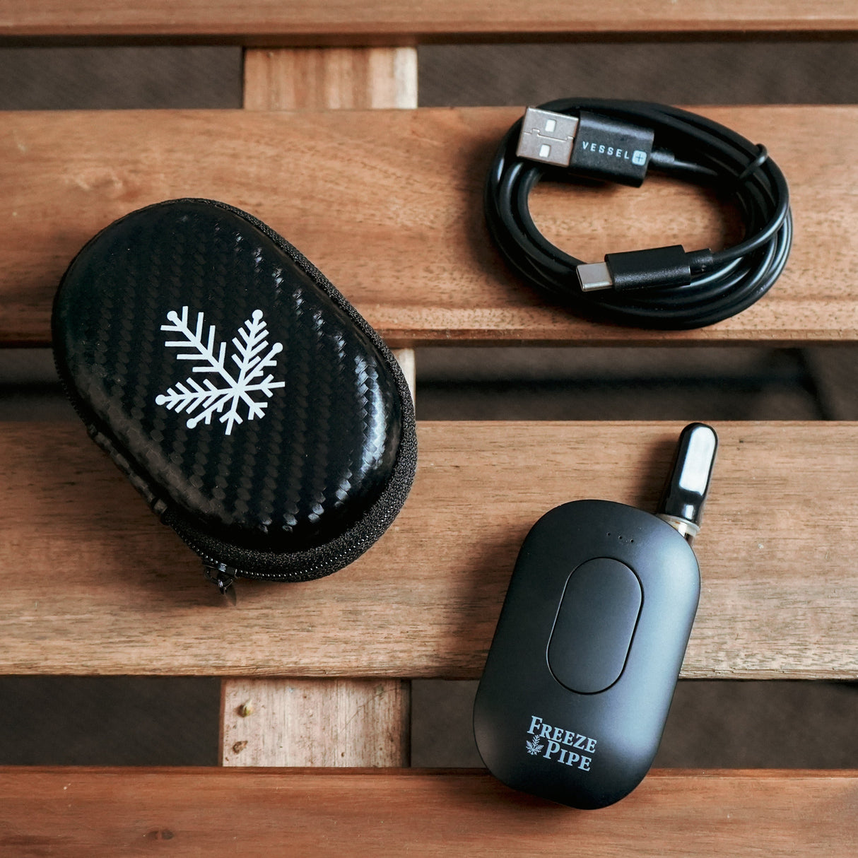 Freeze Pipe Vape Pen with USB Cable and Carrying Case on Wooden Surface
