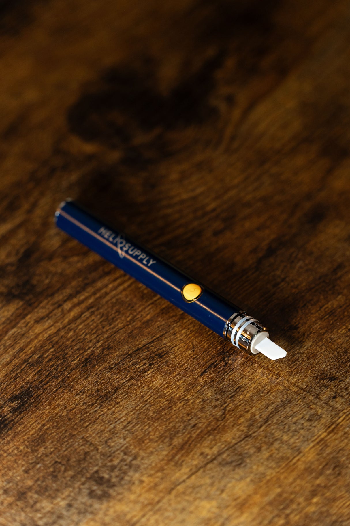 Helio Supply Budder Knife in blue with ceramic tip on wooden surface - electronic dab tool