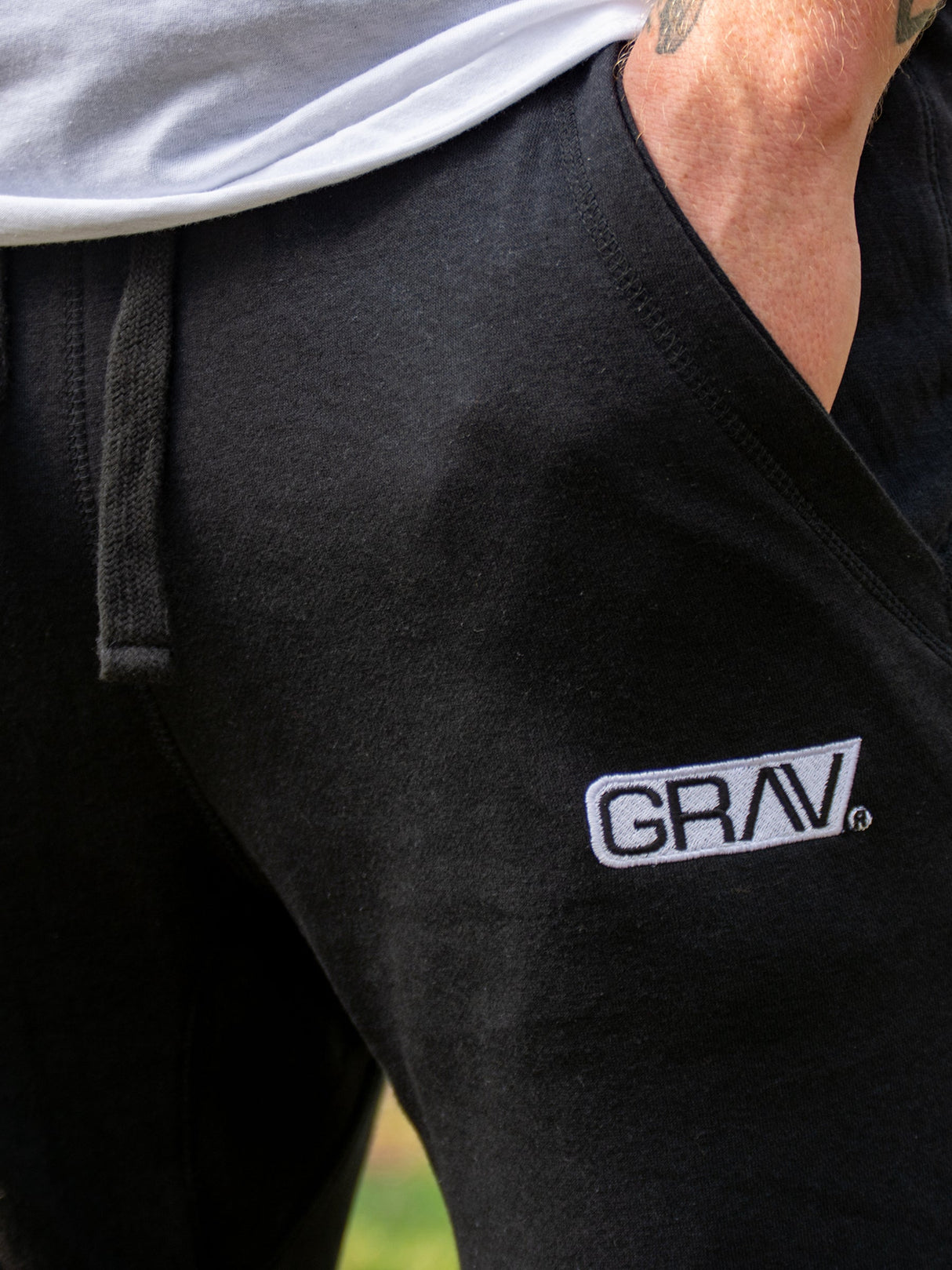 Close-up of black GRAV slim-fit joggers with white GRAV logo on thigh