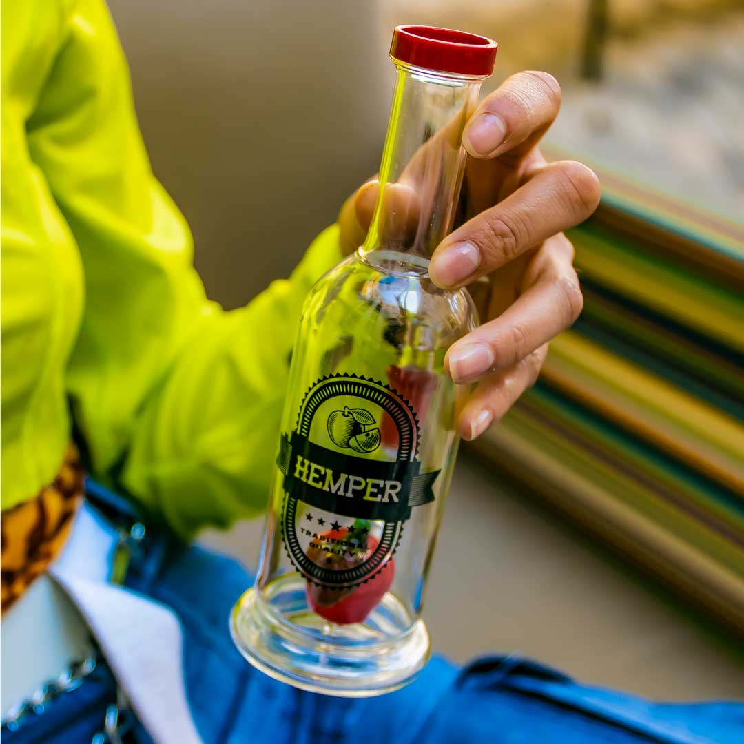 Hemper Apple Cider Bong in clear and red, 7" tall with 14mm joint, held in hand - side view