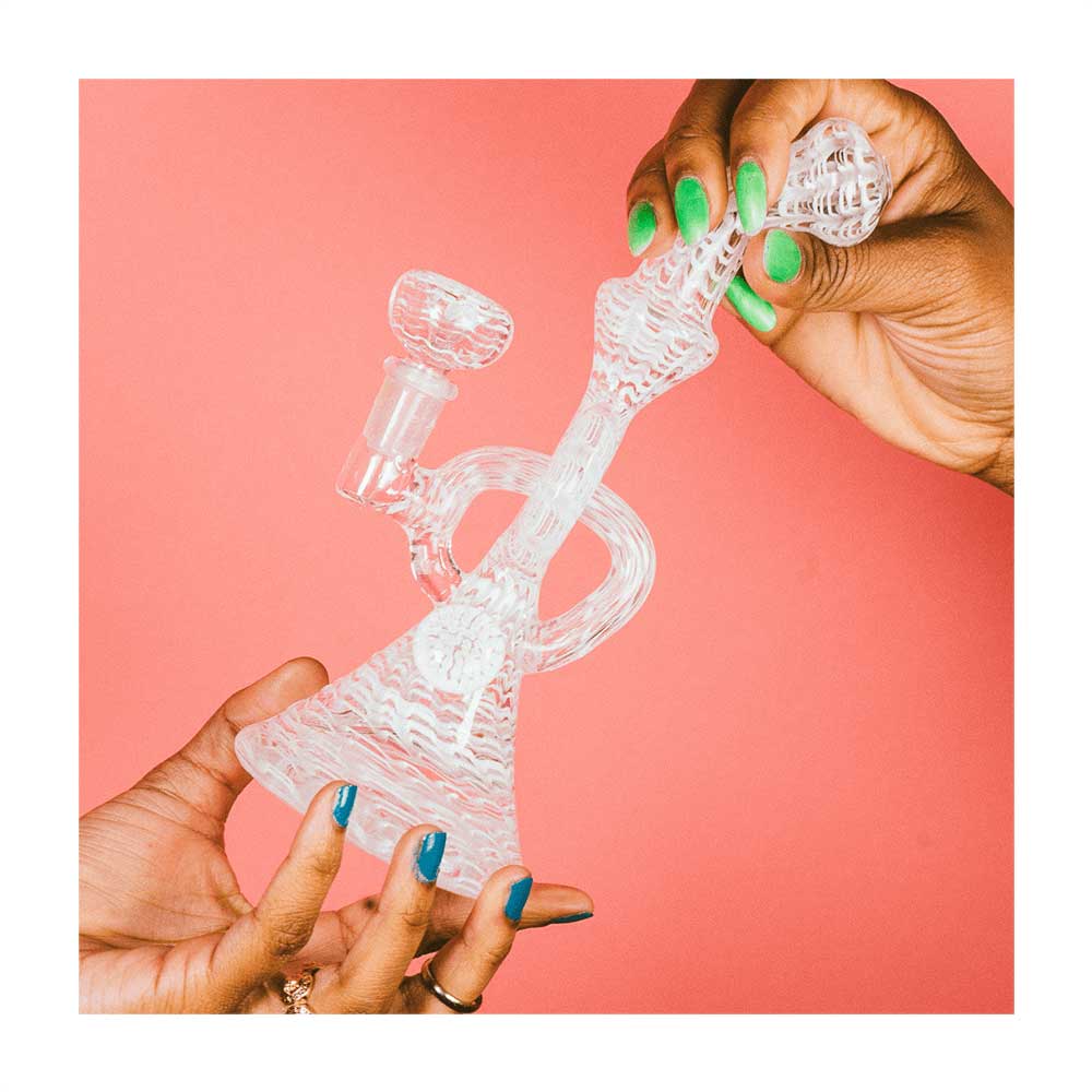 Hemper Snakeskin Bong in clear borosilicate glass held against a pink background