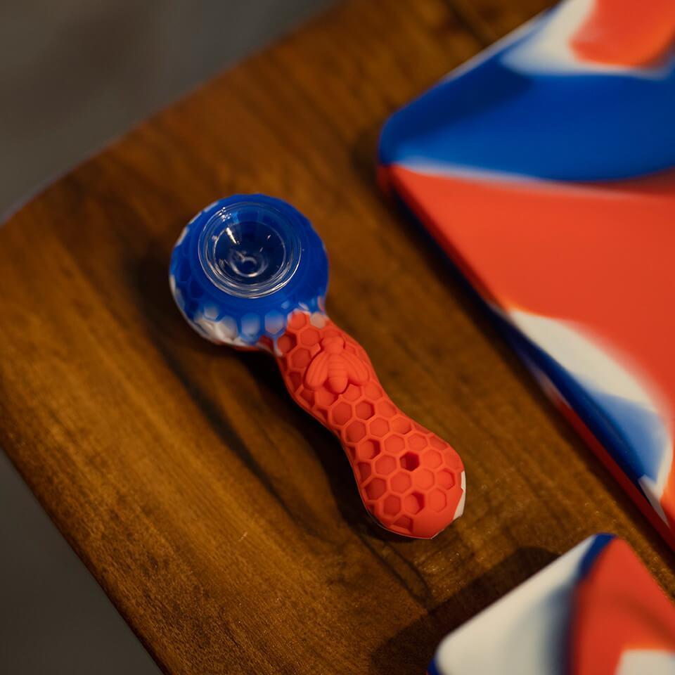 PILOT DIARY Silicone Pipe with Glass Bowl, Red and Blue, Angled View on Wooden Surface