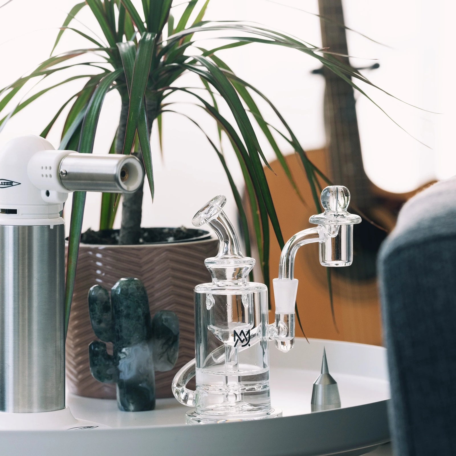 Best Dab Rig for Beginners: What to Buy. Dab rig on table with torch, lifestyle image by DankGeek.com