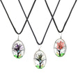 Assorted oval glass pendants with blooming tree designs on black necklaces, front view