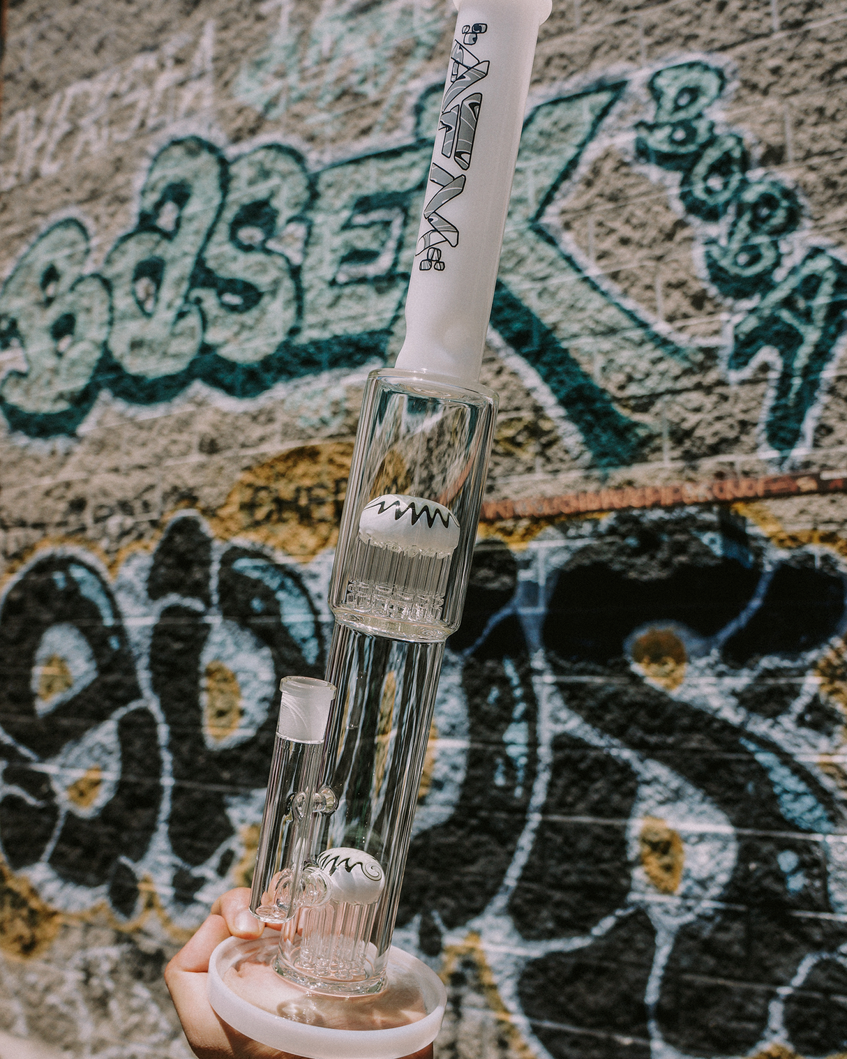 19" AFM Double Hitter Glass Bong with Showerhead Perc and Bent Neck against Graffiti Wall