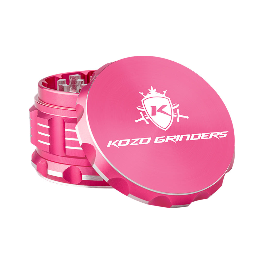 Kozo 3 inch four-piece anodized aluminum grinder in pink, lid tilted open beside the toothed grinding chamber