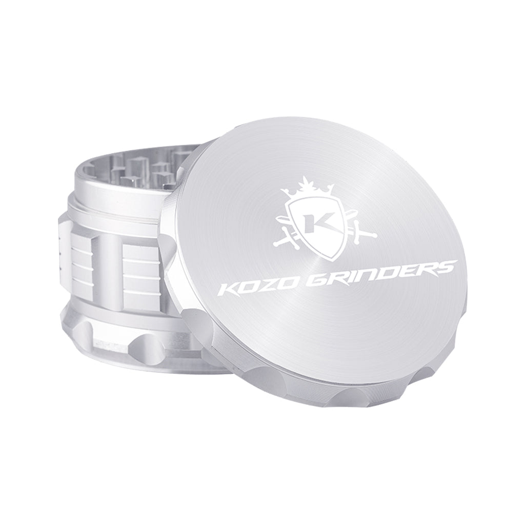 Kozo 3 inch four-piece anodized aluminum grinder in silver, lid tilted open beside the toothed grinding chamber