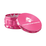 Kozo 4 inch four-piece anodized aluminum grinder in pink, lid tilted open beside the toothed grinding chamber