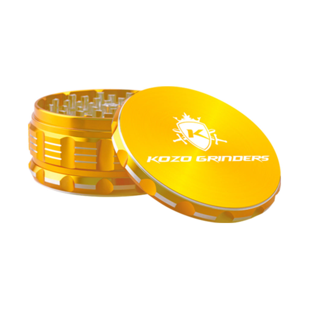 Kozo 4 inch four-piece anodized aluminum grinder in gold, lid tilted open beside the toothed grinding chamber