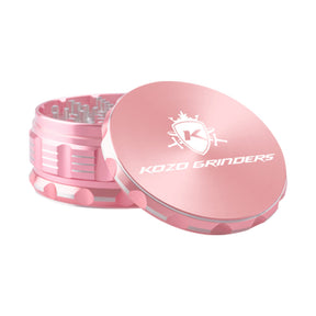 Kozo 4 inch four-piece anodized aluminum grinder in rose gold, lid tilted open beside the toothed grinding chamber