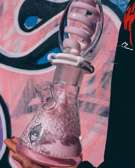 16" AFM Glass Beaker Bong with Freezable Coil and Reversal UFO Pyramid, held against a graffiti background