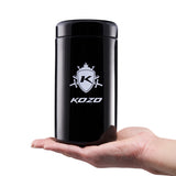 Kozo 1 oz black UV glass storage jar with the airtight lid on, held in one hand to show its size