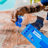 Hand holding BoroBuddy Magnetic Cleaner with blue cleaning pads by poolside, packaging visible