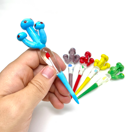 Hand holding AFM Mushroom Glass Dabber Tool in blue with assorted colors in background