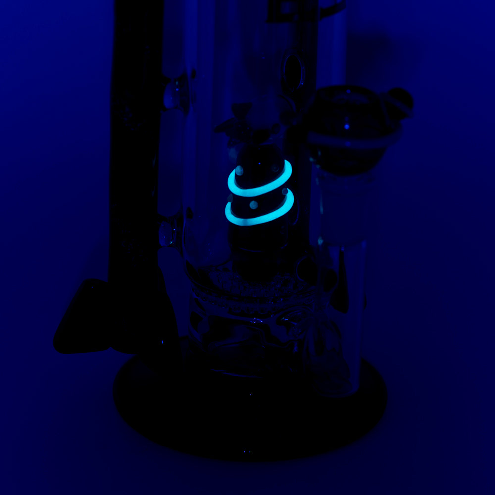 Empire Glassworks Galactic Flagship Water Pipe glowing under black light, side view with intricate details.