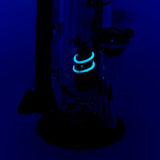 Empire Glassworks Galactic Flagship Water Pipe glowing under black light, side view with intricate details.