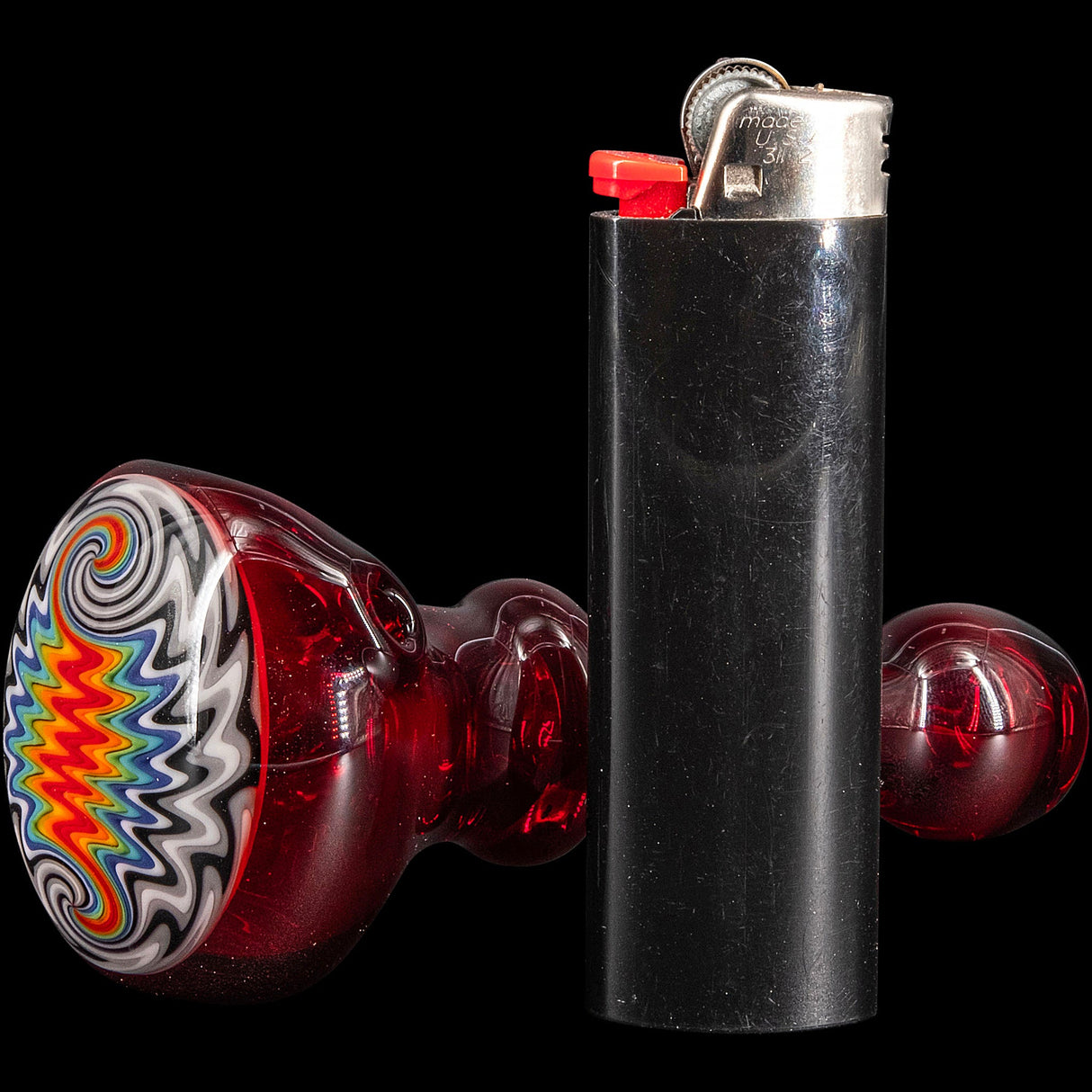 Fire Red Rainbow Reversal Glass Spoon Pipe by Chris Lezak with vibrant design, side view next to lighter