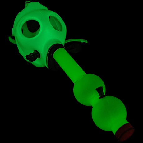 JM Enterprises acrylic gas mask bong glowing green in the dark, diagonal view, mask and tube assembled