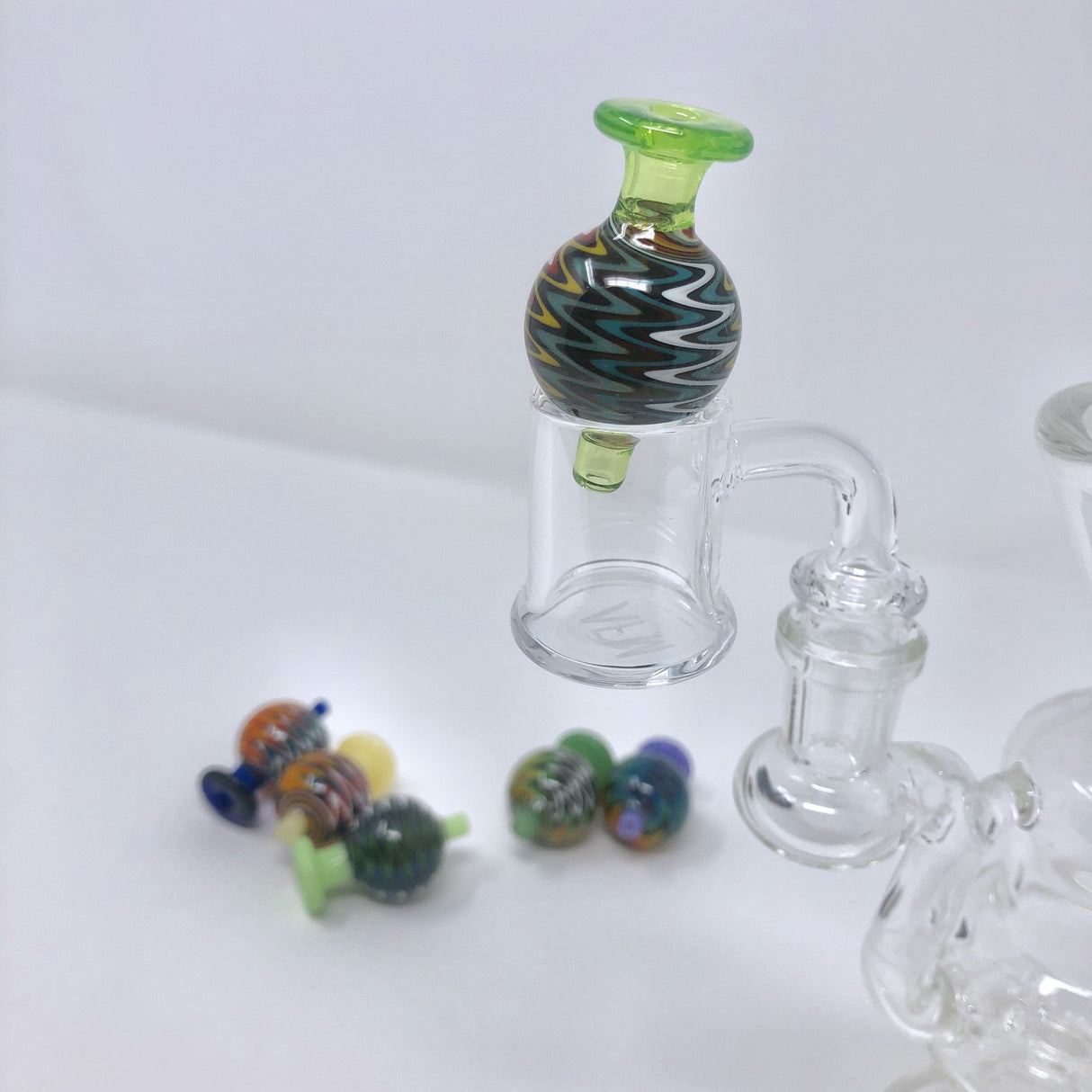 AFM Color Reversal Bubble Carb Cap, vibrant swirl design, shown with glass dab rig parts