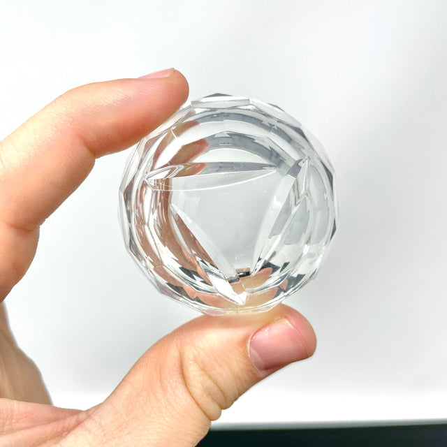 AFM Disc Spinner Carb Cap V3 held between fingers, clear borosilicate glass, close-up view