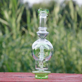 Calibear Ball Rig Carta Attachment in clear glass with green accents, front view on wooden surface