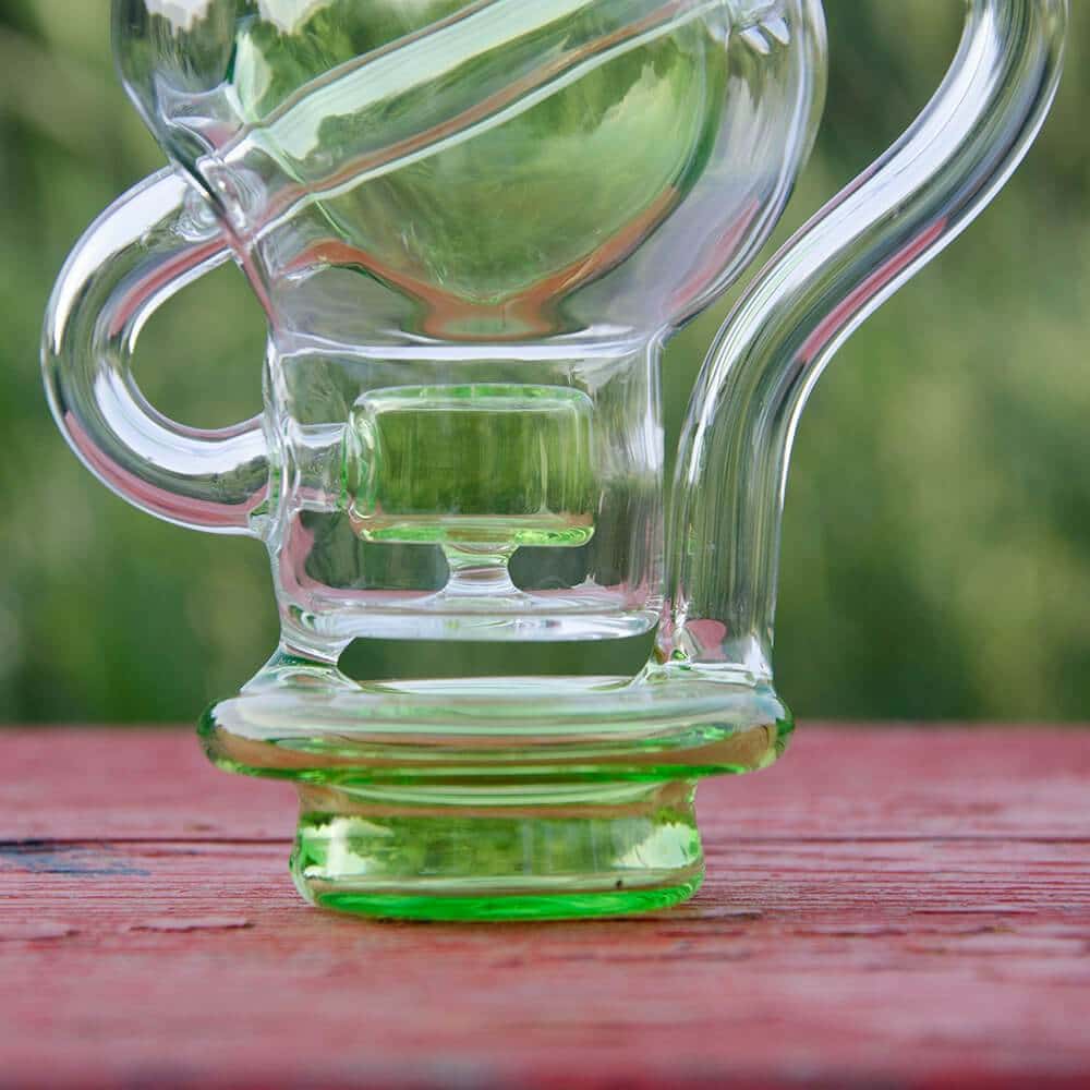 Calibear Ball Rig Carta Attachment in clear glass with green accents, side view on wooden surface