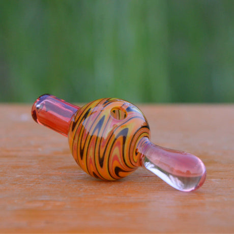 Calibear Wigwag Bubble Carb Cap in Borosilicate Glass - Side View on Wooden Surface