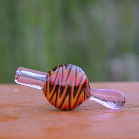 Calibear Wigwag Bubble Carb Cap in Red, High-Quality Borosilicate Glass, Side View on Wooden Surface