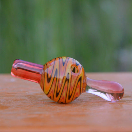 Calibear Wigwag Bubble Carb Cap in yellow, high-quality borosilicate glass, angled side view on wooden surface
