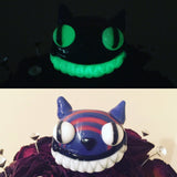 Chameleon Glass Cheshire Cat Pipe with glow effect, displayed in dark and light settings
