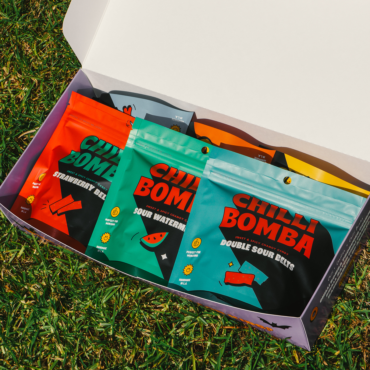 Chilli Bomba's Mystery Box open on grass, showing assorted spicy snacks