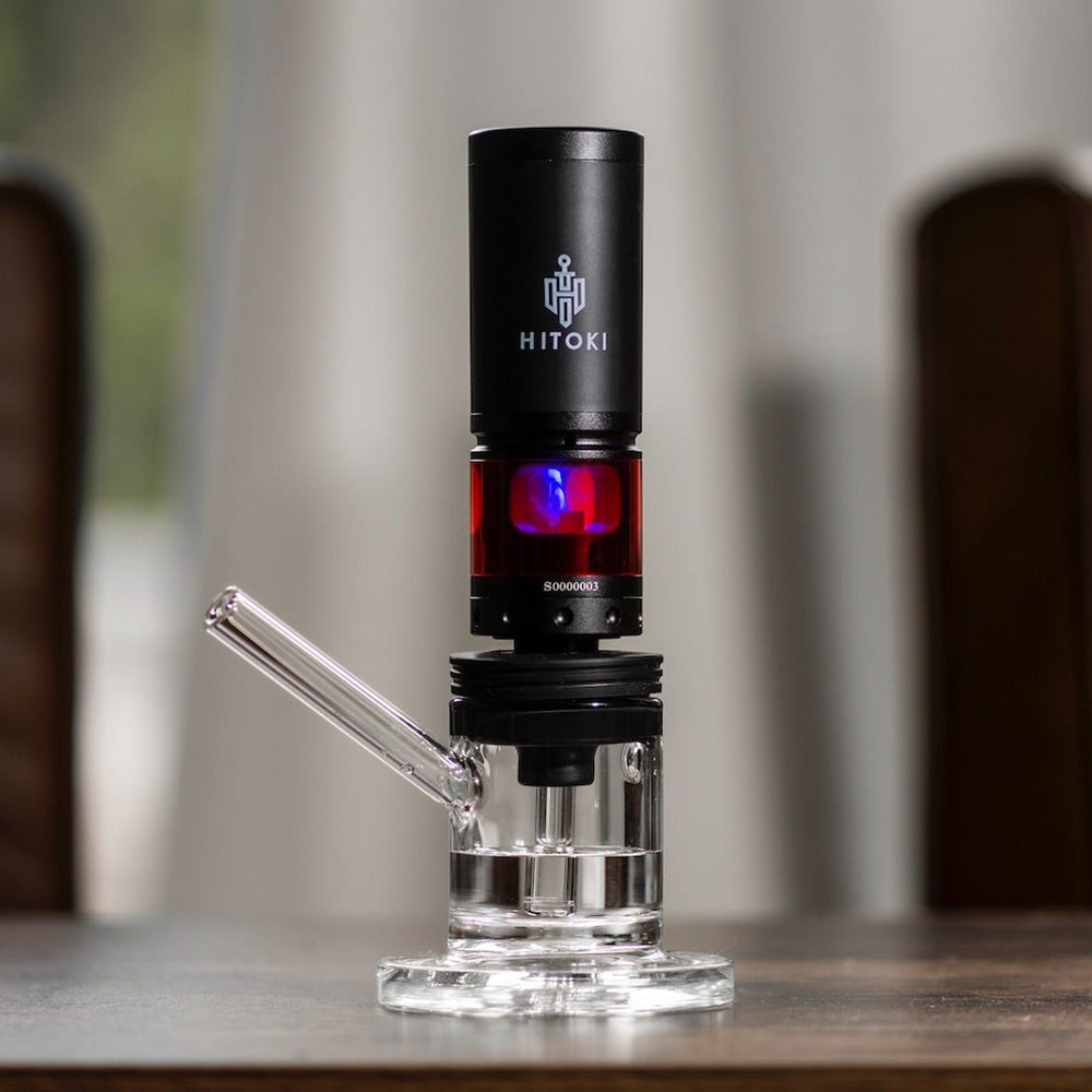 Hitoki Saber Laser Combustion Vaporizer with Water Pipe Attachment, front view on wooden table