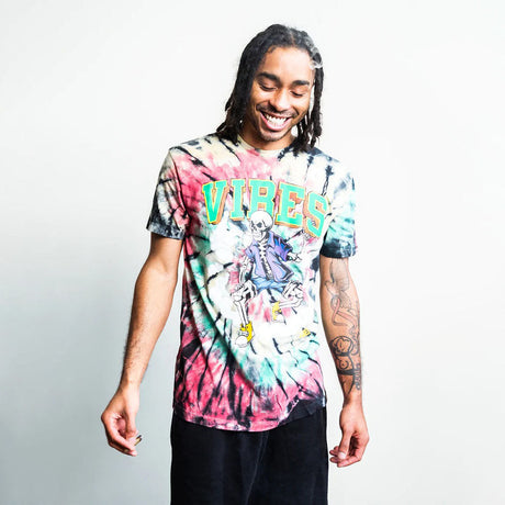 Smiling model wearing VIBES Skull & Cones Tie Dye T-Shirt with rasta colors, front view