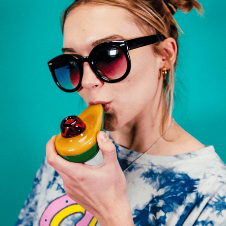 Woman using Goody Avocado Hand Pipe by Goody Glass, front view with vibrant colors