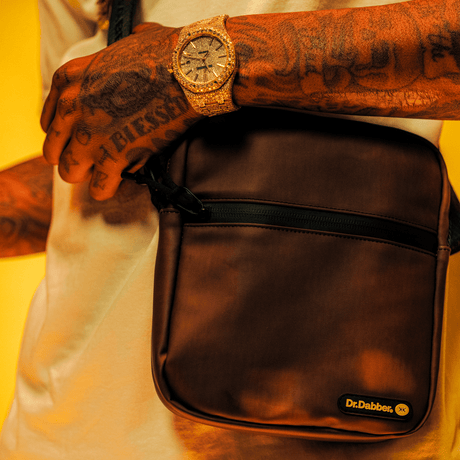 Dr. Dabber XS™ Khalifa Kush Edition Vaporizer in a sleek carrying case, modeled on person's shoulder