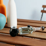 Freeze Pipe Revolver on wooden table, clear glass with black accents, side view, ready to use