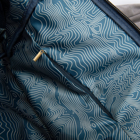 Close-up view of Revelry Supply Drifter Rolltop Backpack showing the smell-proof canvas material and pattern.