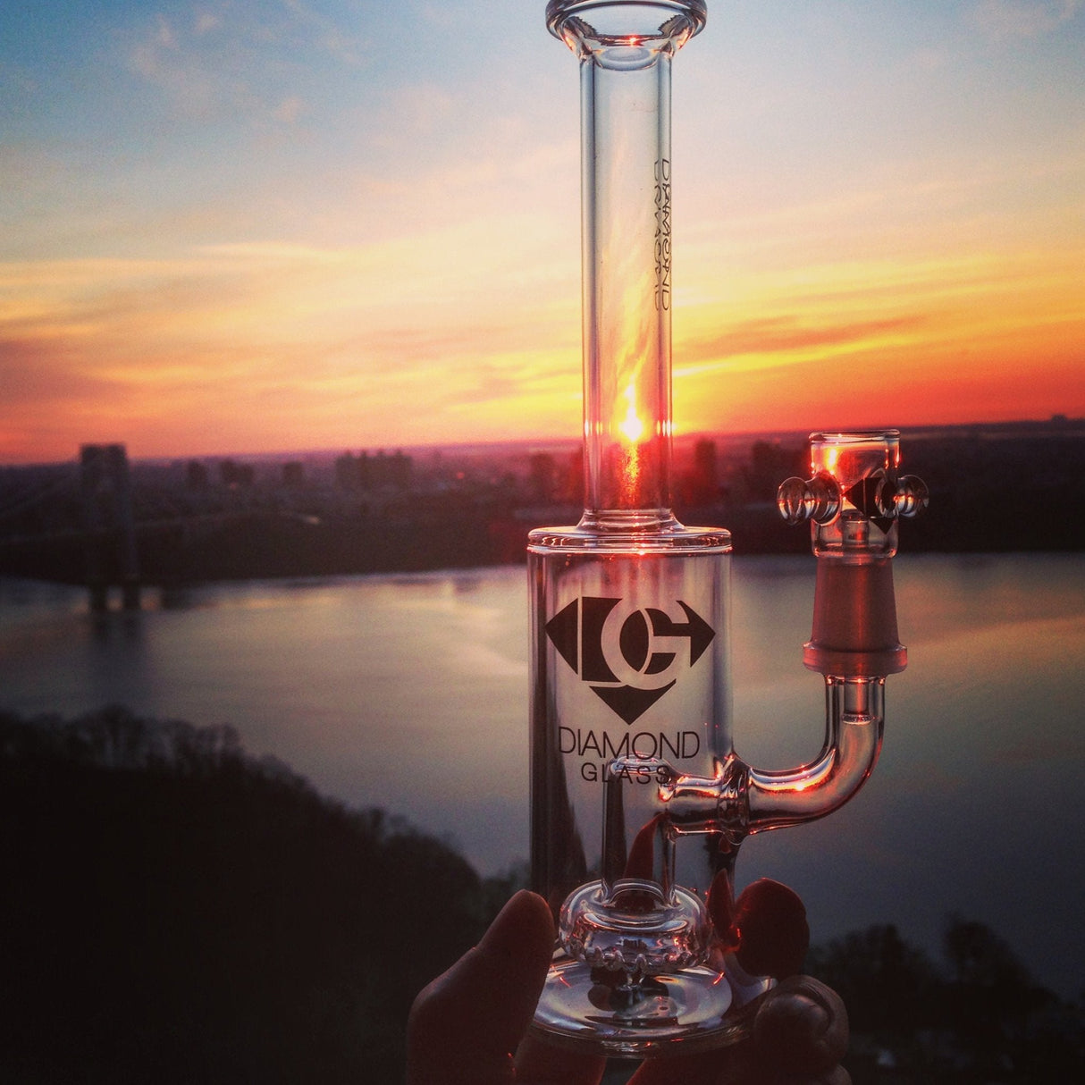 Diamond Glass Showerhead Dab Rig with Sunset Backdrop, held in hand for scale, ideal for concentrates