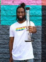 Smiling person wearing GRAV Gay Pride Logo T-shirt in white, front view, colorful background