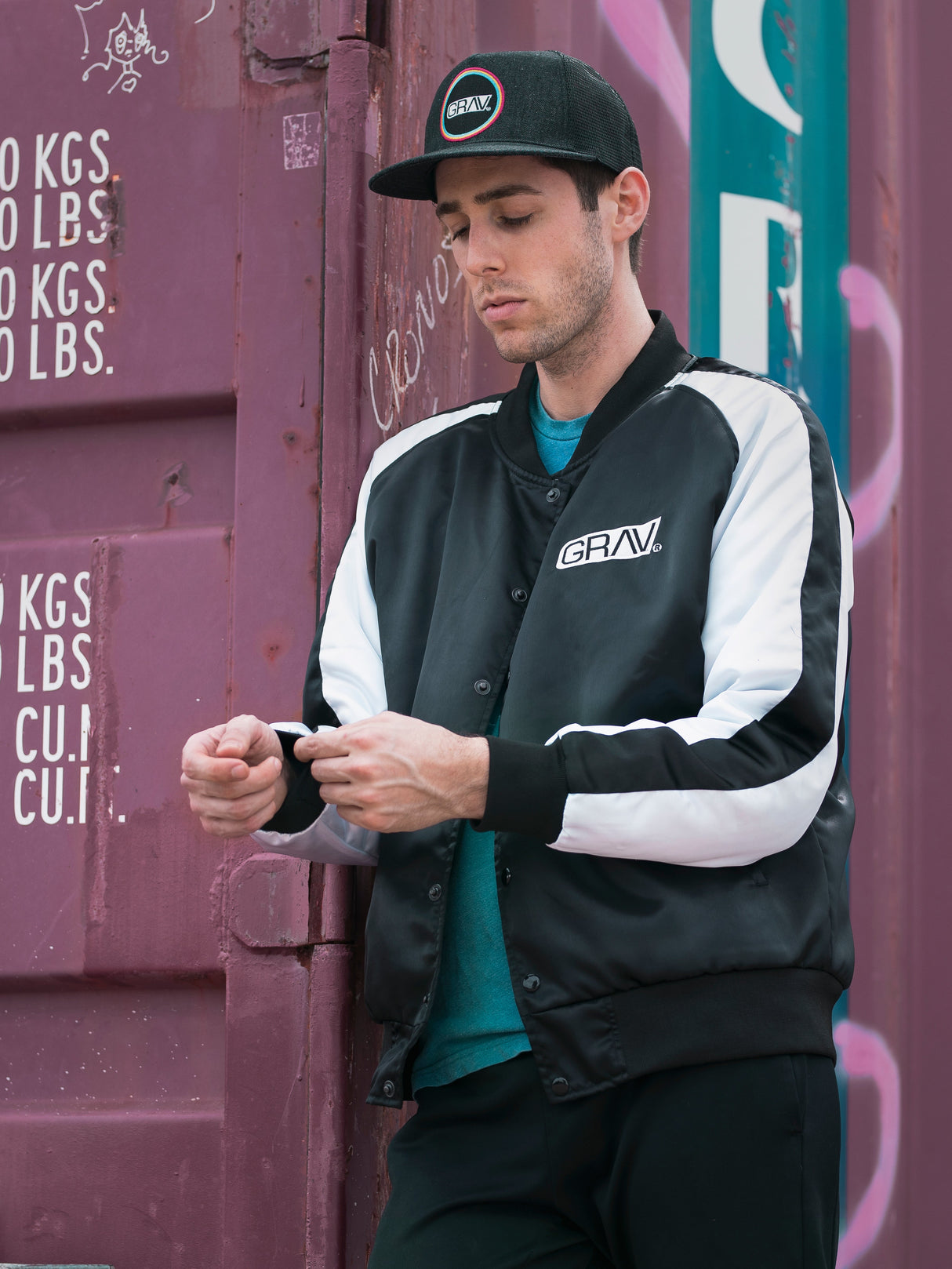 Man wearing GRAV Satin Bomber Jacket in urban setting, side view with casual pose